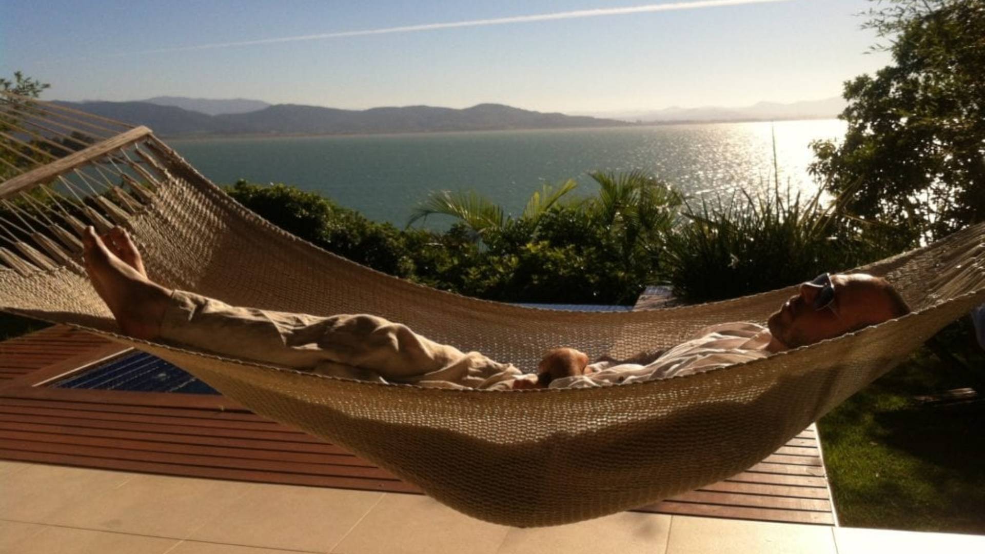 MAN IN HAMMOCK BY THE SEA