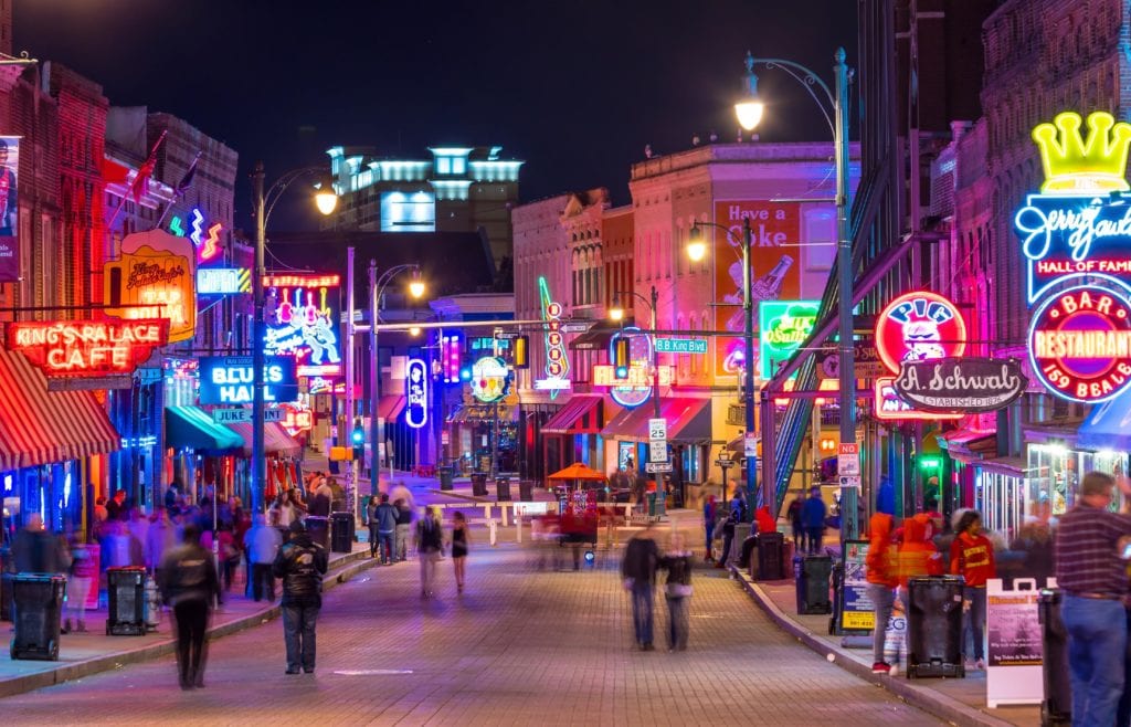 Neon signs line Beale Street in Memphis as blurred people walk down the street