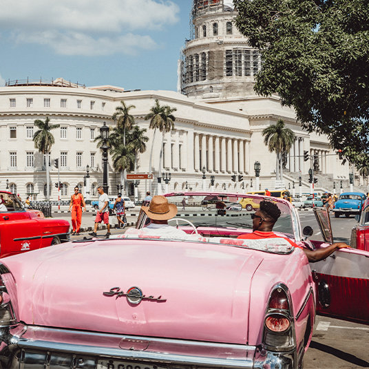 The back of a pink classic car driving through Havana