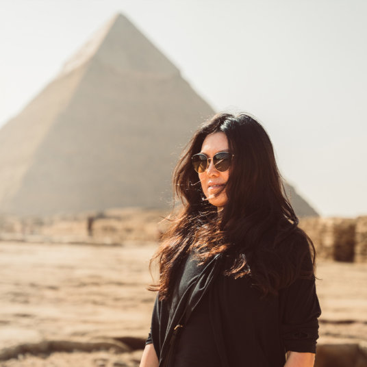 Woman in sunglasses in front of the Giant Pyramid of Giza, Egypt
