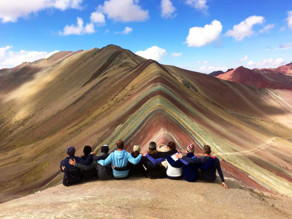 A group of people sat down in front of the Rainbow Mountain (Vinicunca) in Peru