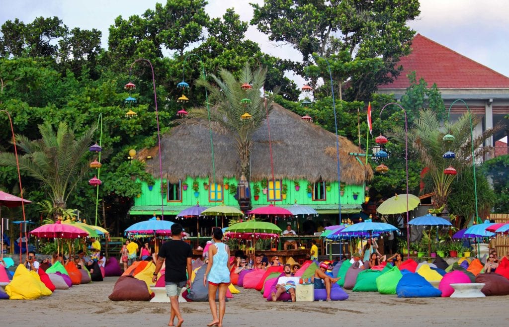 The bright green Seminyak beach resort in Bali lined with multi-coloured parasols and bean bags
