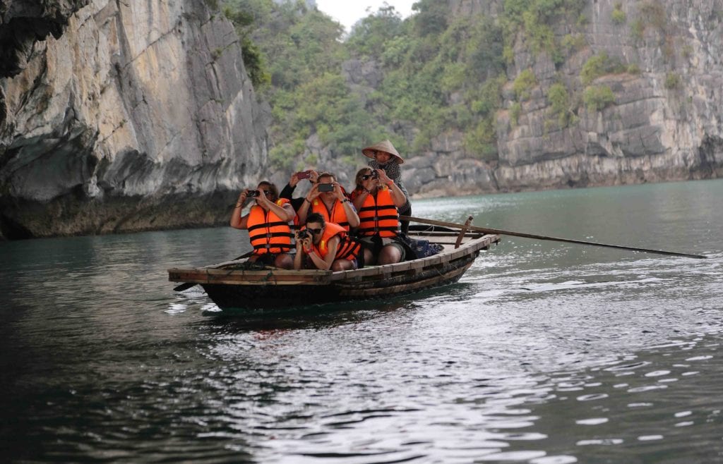 Group of flashpackers in boat taking photos