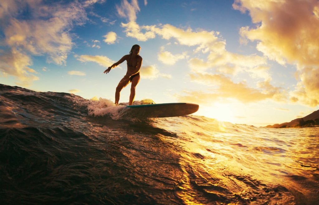 determined woman surfing at sunset