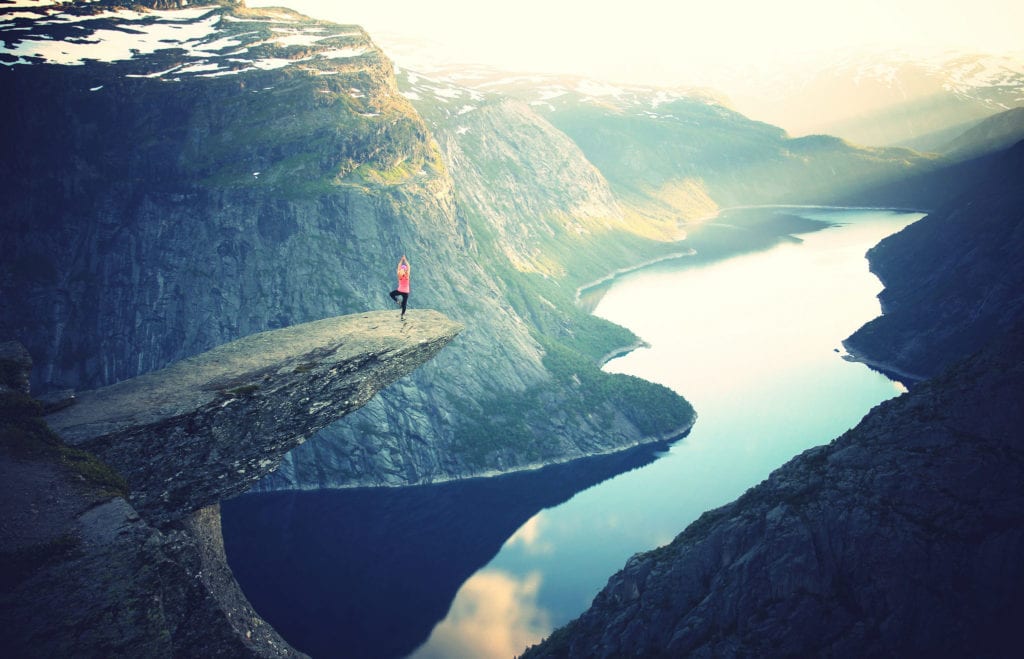 Woman doing yoga on mountain ledge
