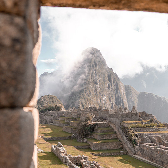 An image of a misty Machu Pichu through a stone window