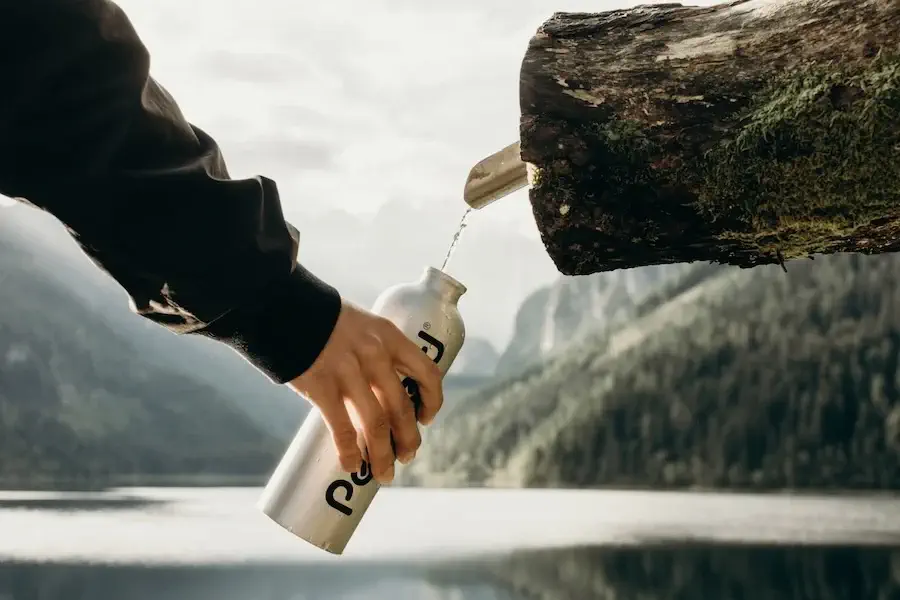 water bottle being filled from log