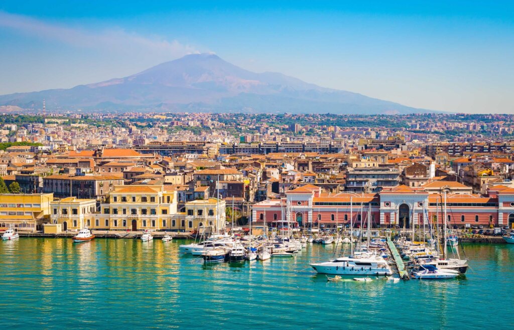 A port in Sicily with a view of the boats, coloured houses and Mount Edna