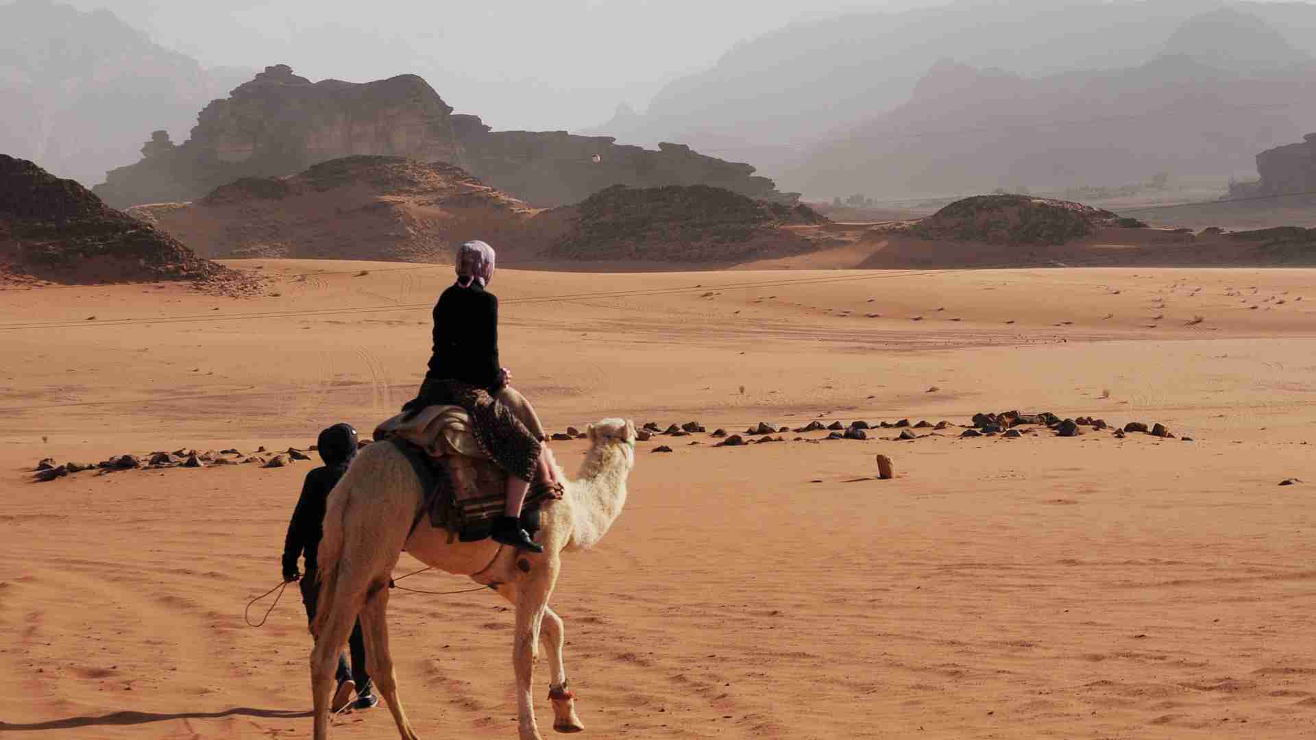 riding a camel across desert in jordan