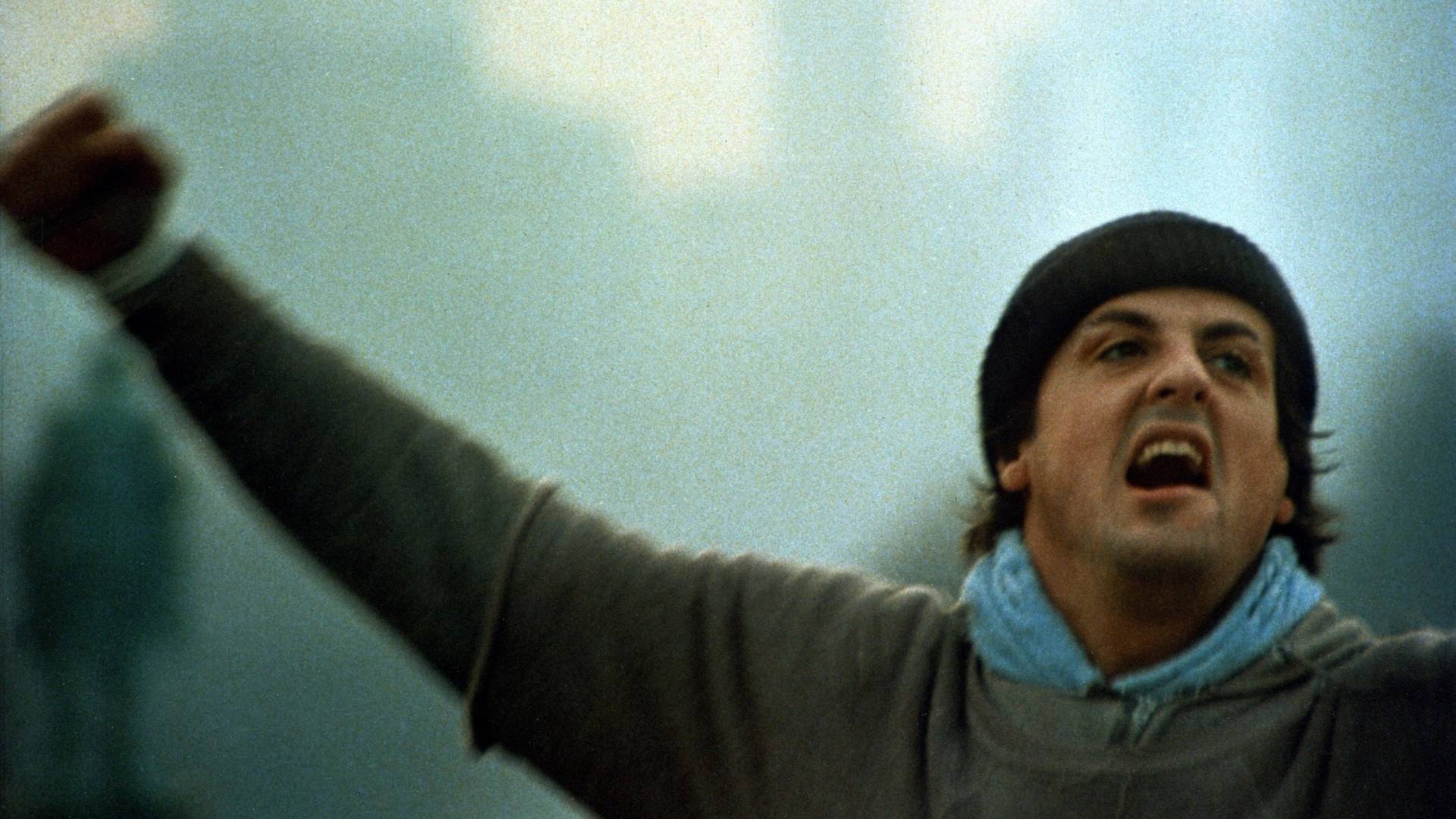 sylvester stallone in rocky wearing a hoodie and looking happy