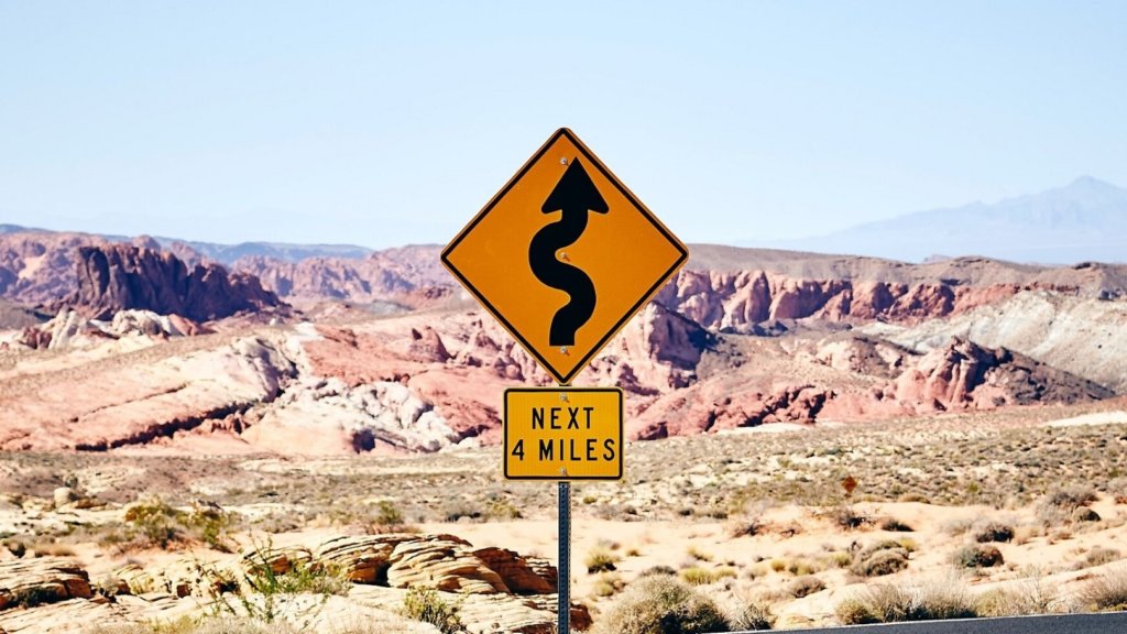 A swerve road sign in front of a rocky landscape
