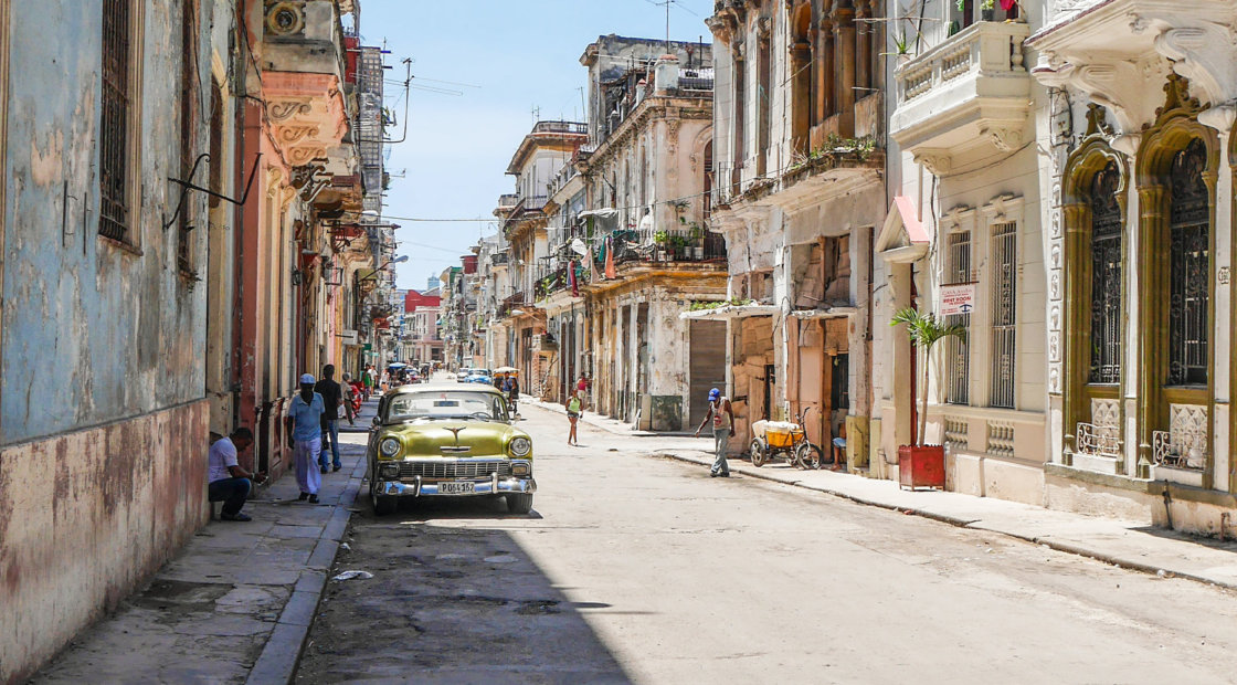 A green classic car parked on the streets of Havana