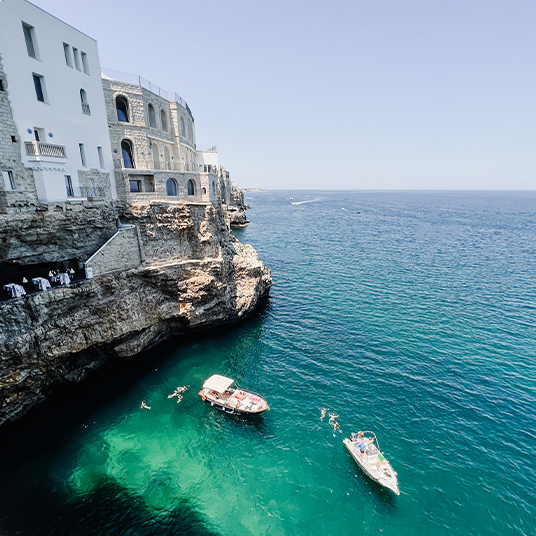 Two boats in the water off the coast of Polignano a Mare