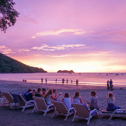 People on sunloungers observing the sunset on Manuel Antonia Park in Costa Rica